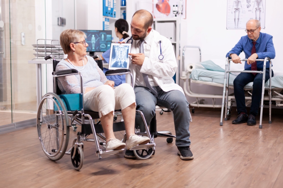 doctor-with-stethoscope-using-tablet-pc-during-examination-handicapped-woman-wheelchair